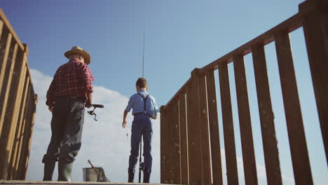 Bottom-view-of-a-grandfather-and-his-grandson-fishing-from-a-wooden-bridge-in-a-lake