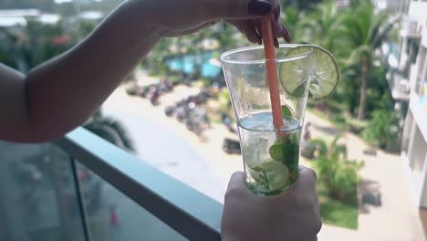 lady holds frozen mojito and enjoys view from nice balcony