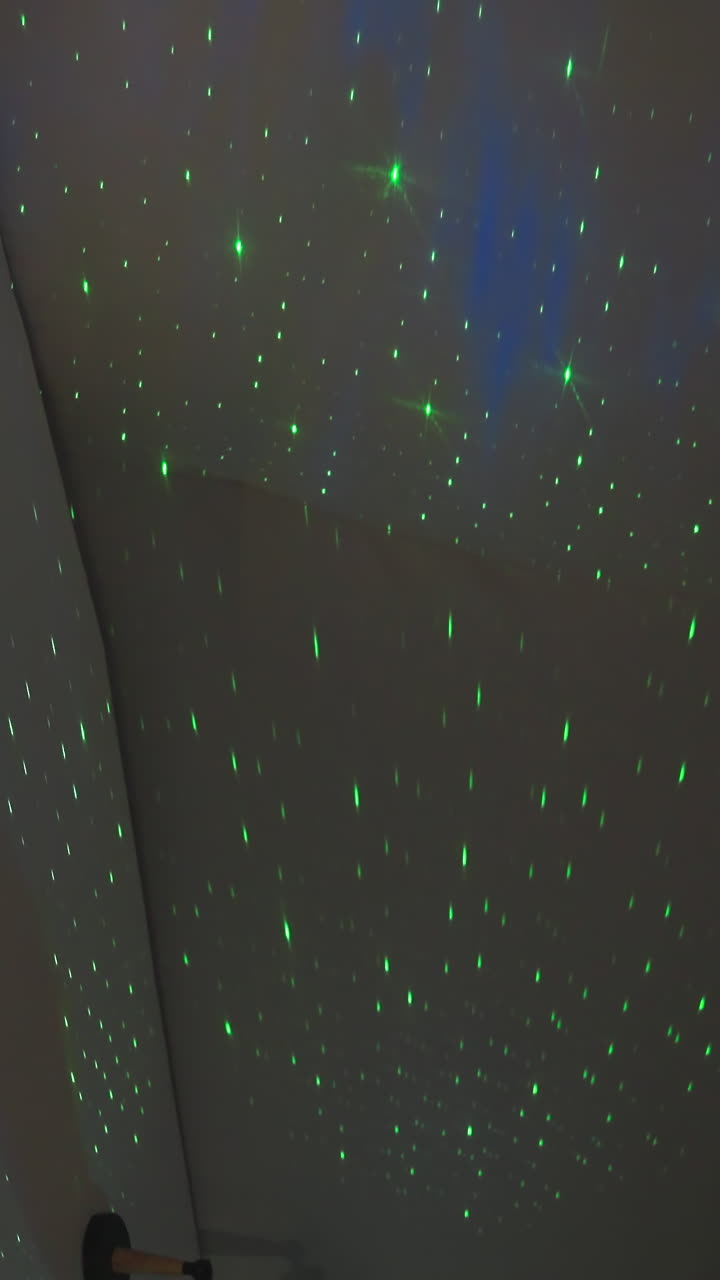 Starry sky light imitation by projector in bedroom. Spellbound green lights on white semi-spherical wall of glamping house. Fairy tale home device