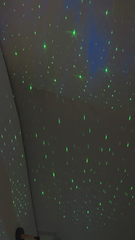 imitación de la luz del cielo estrellado por el proyector en el dormitorio. luces verdes encantadas en la pared semiesférica blanca de la casa de glamping. dispositivo doméstico de cuento de hadas