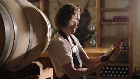 authentic shot of successful male sommelier is tasting a flavor and checking white wine quality poured in transparent glass in a wine cellar.