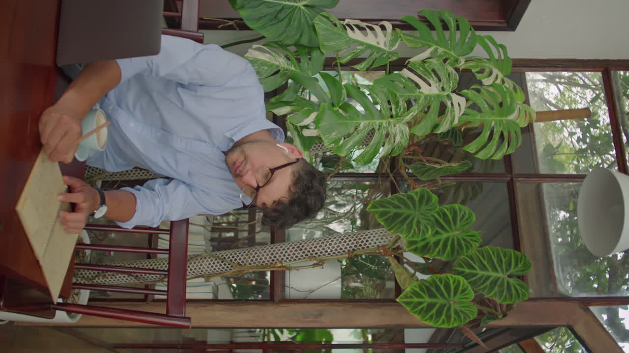 Businessman Using Laptop and Taking Notes in Outdoor Cafe