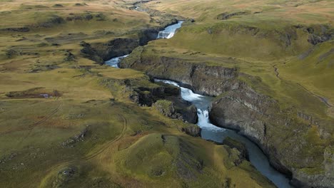 beautiful waterfall and river in green, summertime iceland landscape - aerial