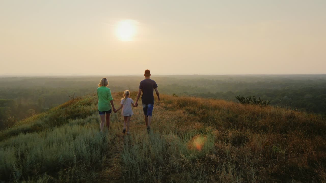 una familia con un niño camina hacia el sol