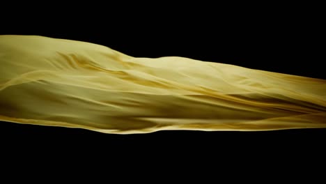 Yellow-Silk-Cloth-Blown-By-The-Wind-In-Black-Background---studio-shot