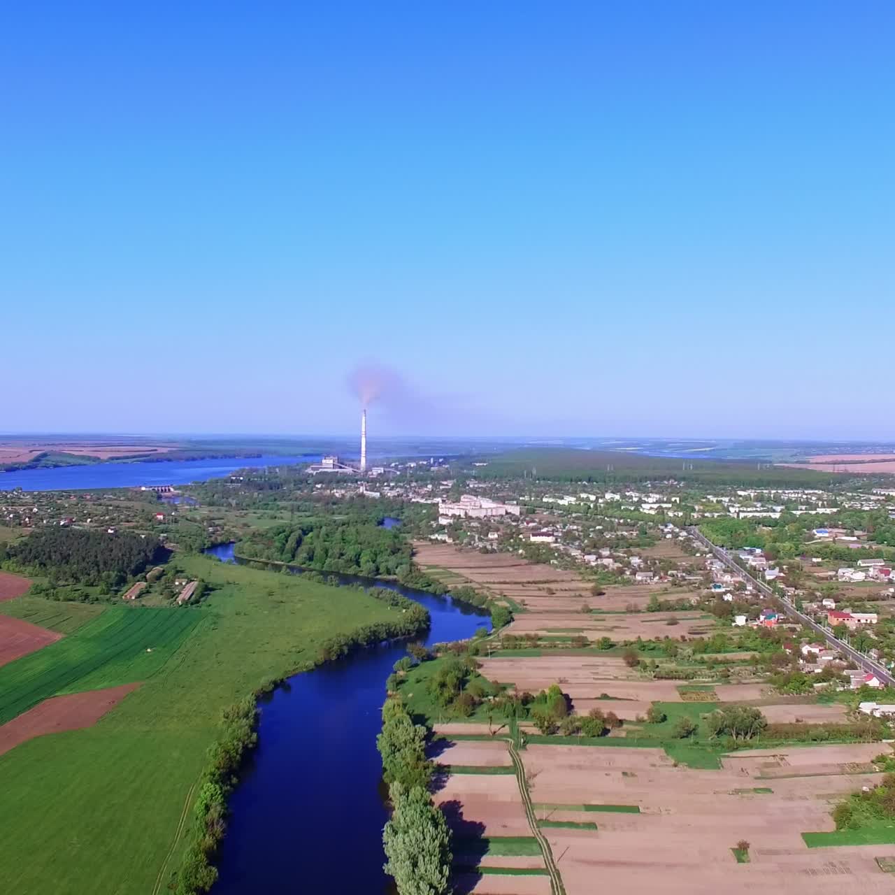Outstanding panorama of city locating in beautiful nature. Dark blue thin river dividing the area. Blue sky at backdrop