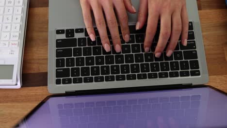 person typing on a laptop keyboard at a desk
