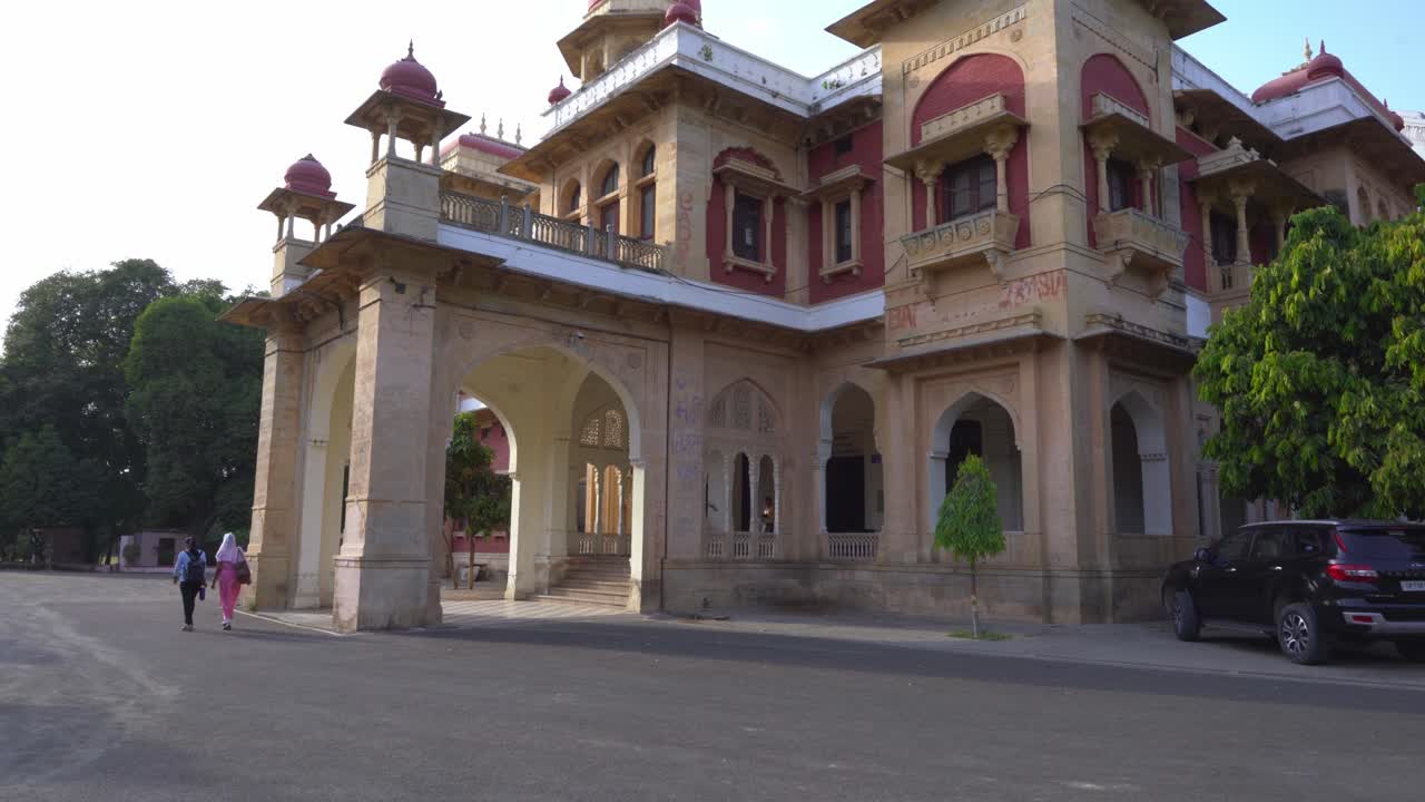People walking past a historic university building in India