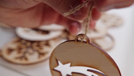 threading natural string through wooden christmas decoration