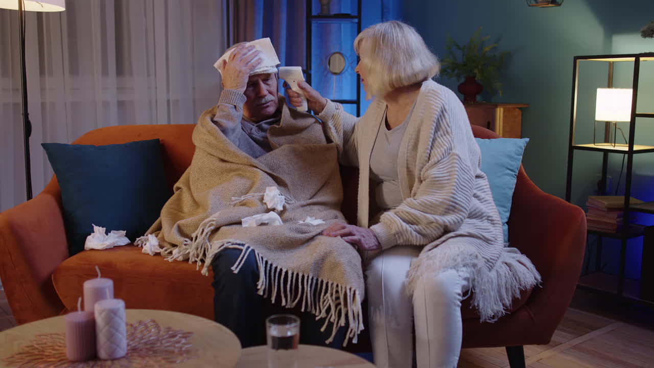 코로나 바이러스 봉쇄 기간 동안 고령 부부는 비접촉 디지털 온도계를 사용하여 온도를 측정합니다.