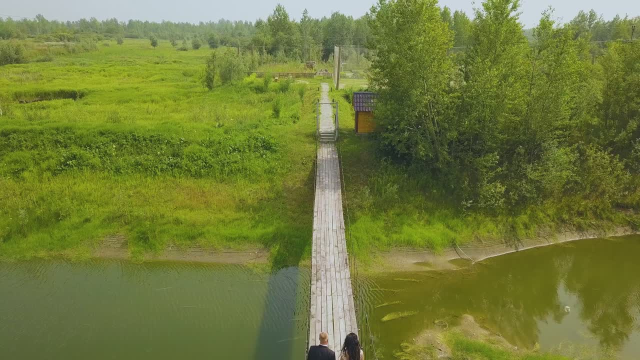 pareja casada camina por el viejo puente sobre el río vista aérea