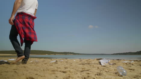 Junger-Mann-Wirft-Plastikflasche-Am-Strand