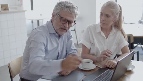 senior boss in eyeglasses discussing with female assistant