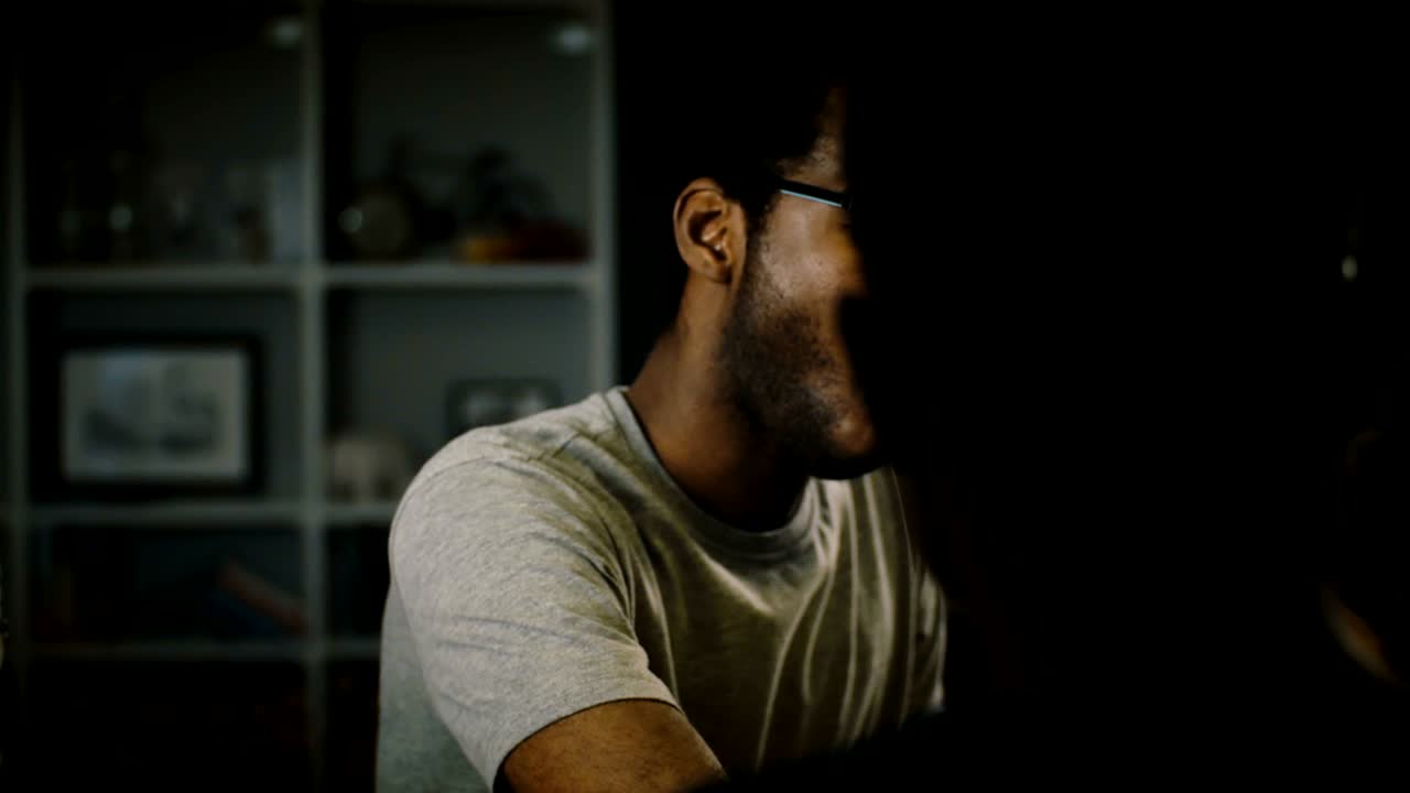 African American casual young man in glasses eating pizza at party. Happy friends enjoy fast food in the kitchen at home