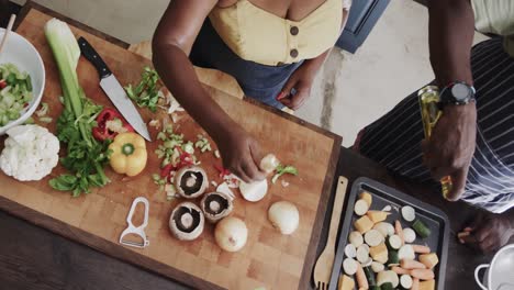 Senior-african-american-couple-throwing-food-waste-out-and-cooking-in-ktichen-in-slow-motion