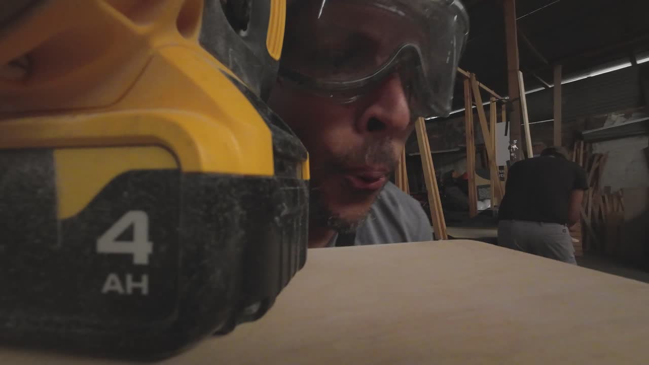 Craftsman Inspecting Wooden Surface with Sanding Machine in Workshop