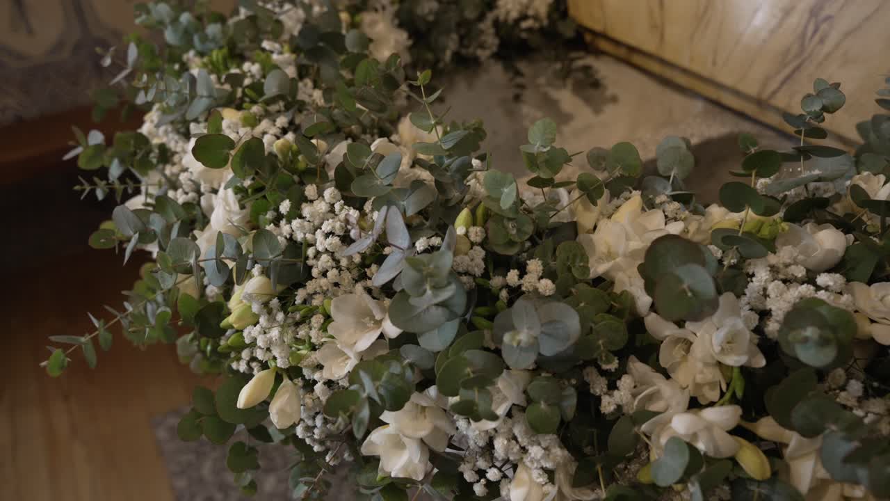 Close up of white funeral wreath with greenery and reflection indoors