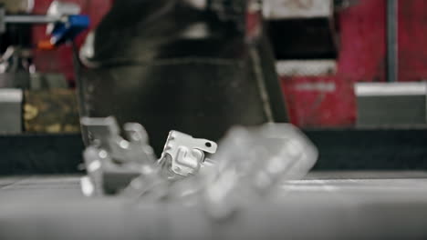 close up of raw car parts falling on a conveyor belt after being molded in a modern automated factory