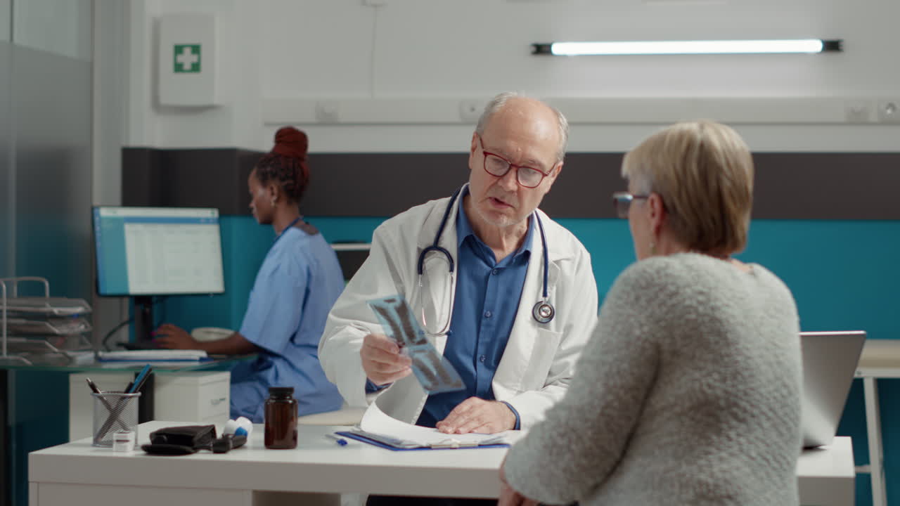 Male physician showing x ray results diagnosis to old woman