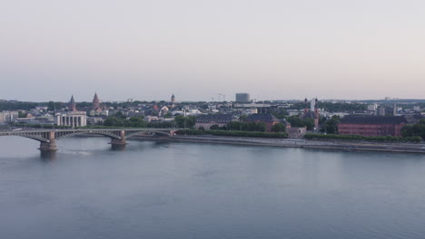 aerial ascending drone view of mainz with dom, castle, theodor heuss bridge and cityscape at sunset – rhine river, germany