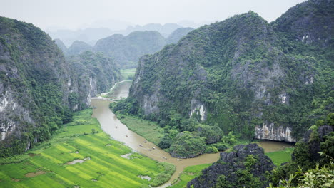 a static timelapse capturing ninh binh’s river with numerous tourist boats and the majestic limestone mountains as a stunning backdrop.