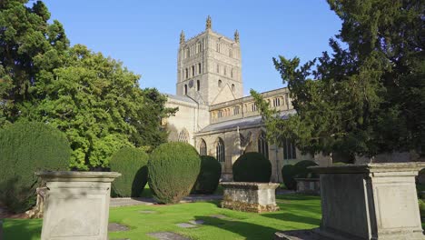 the norman or romanesque tower of the medieval edifice of tewkesbury abbey with the old grave stones of the graveyard in the foreground