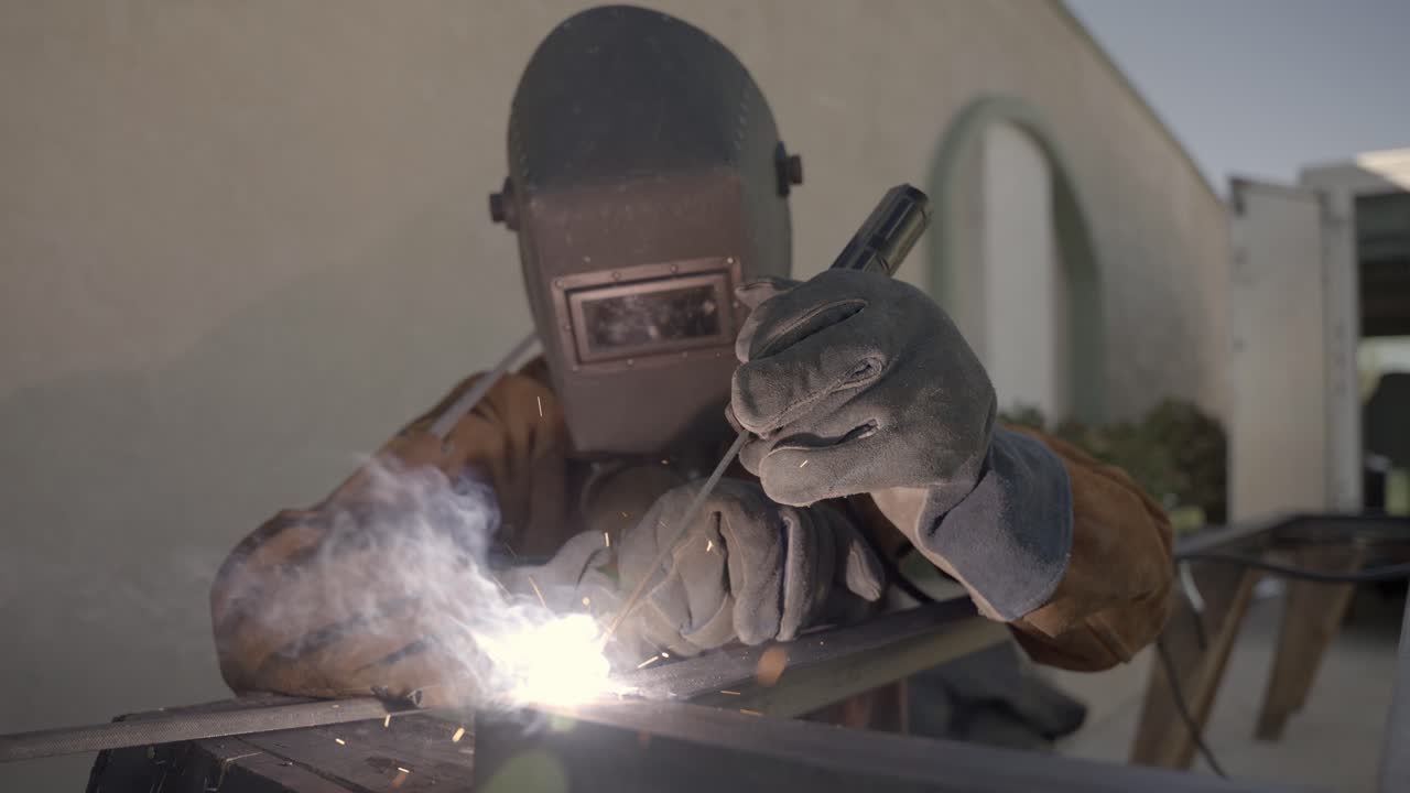 Person with protection mask is welding a metal object, sparks shooting