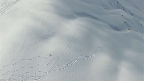 lonely person skiing on white remote mountain slope, aerial view