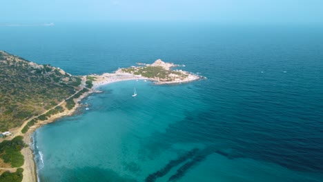 Clear-blue-turquoise-and-calm-water-at-a-natural-sand-beach-coast-bay-in-Sardinia,-Italy-with-sun-and-sailing-ship