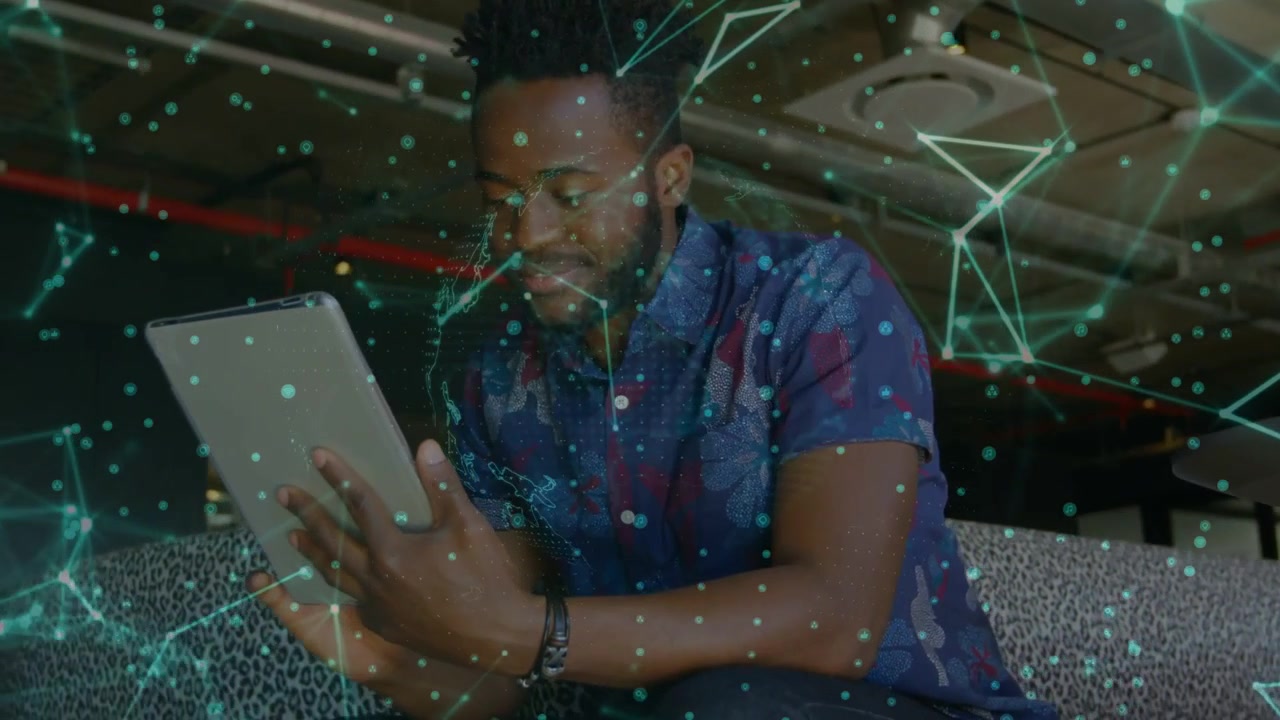 Man tapping tablet in open office, activating green network overlay and analyzing tech data