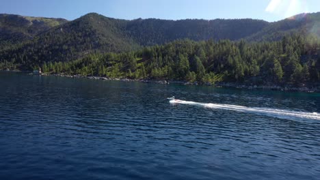 lancha rápida navegando y dejando estela en el agua con exuberantes bosques verdes y montañas