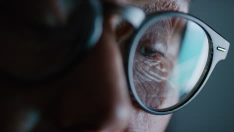 pantalla de ojo macro de cerca que se refleja en las gafas anciana navegando en línea por la noche