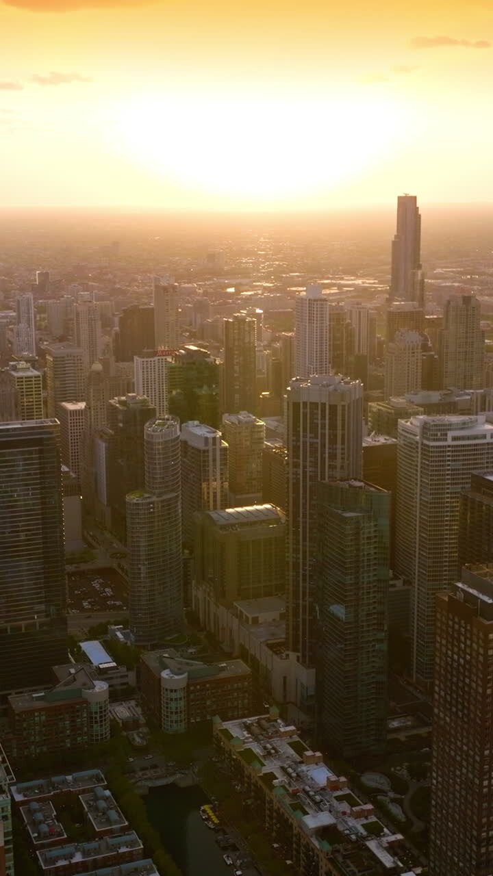 Tremendous skyscrapers in the light of downing sun. Stunning city panorama and hazy skyline in the rays of sunset. Top view. Vertical video