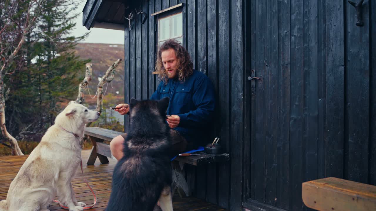 A Man Shares Treats With His Two Dogs Outside a Rustic Cabin in Reinsjøen, Åfjord, Trøndelag, Norway - Close Up