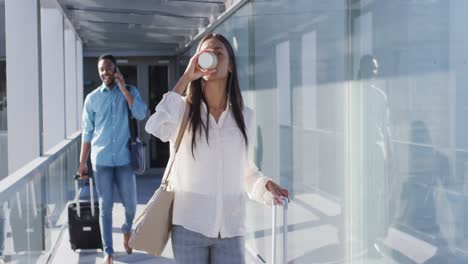 Video-of-diverse-man-and-woman-walking-with-suitcases-and-coffee