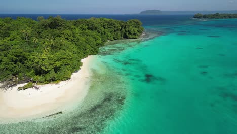 a drone flies over a lush green island at port olry on the island of espiritu santo