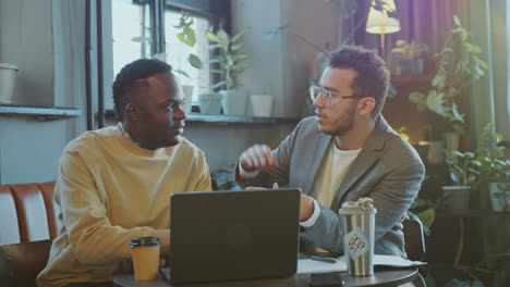 two young businessmen discussing plan on laptop in coworking office