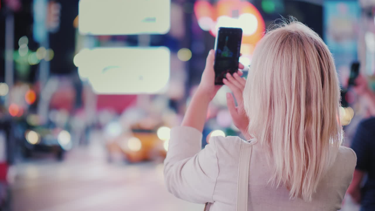 turist tar bilder med en smarttelefon på den berømte times square i new york bakovervisning