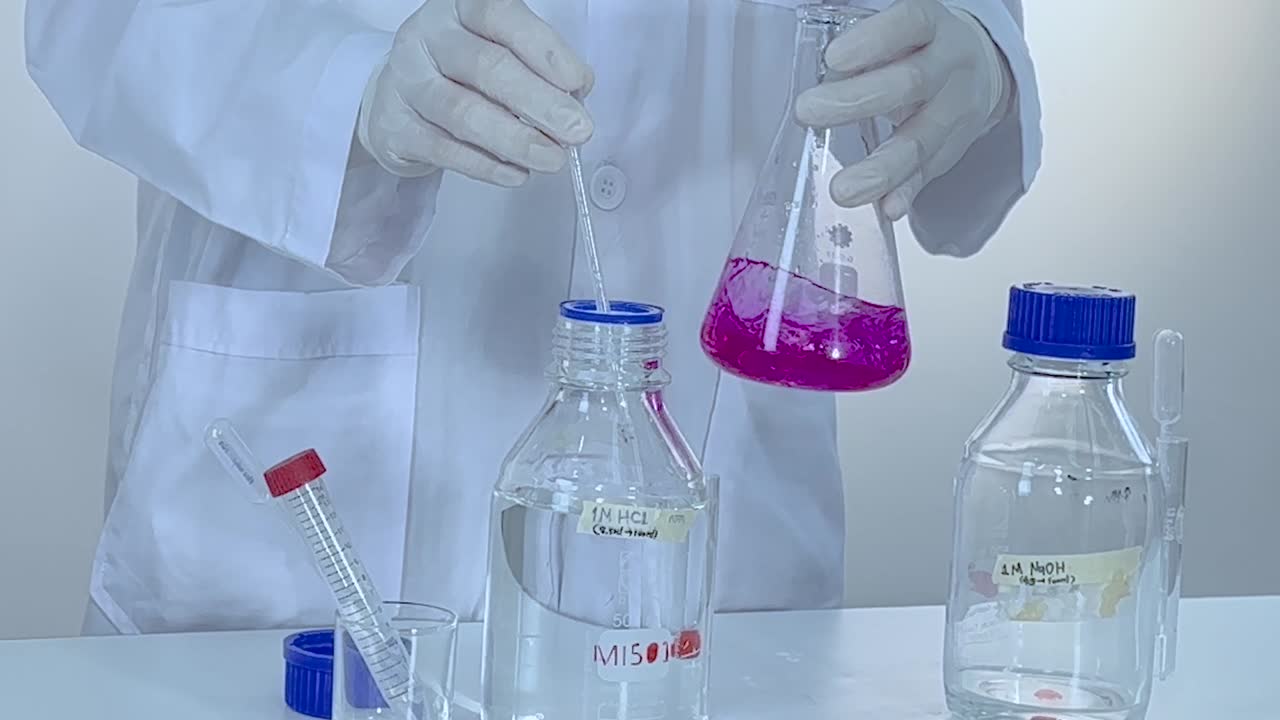 A scientist handles a pink solution in a flask, showcasing laboratory procedures.