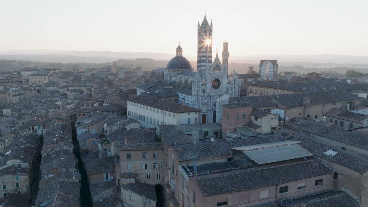 vista aérea de siena, toscana, italia al amanecer con la torre del mangia y el resplandor del sol a través del duomo de siena, en 4k