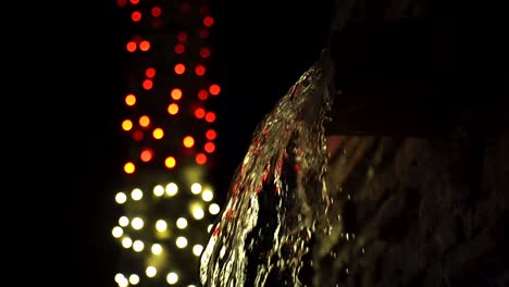 hoja de agua de la fuente de piedra iluminada por luces de cadena bokeh
