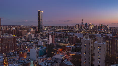 Toma-Aérea-De-Hiperlapso-De-La-Ciudad-En-El-Crepúsculo.-Oscureciendo-Gradualmente-El-Cielo-Sobre-Un-Gran-Puente-Atirantado.-Manhattan,-Ciudad-De-Nueva-York,-Estados-Unidos