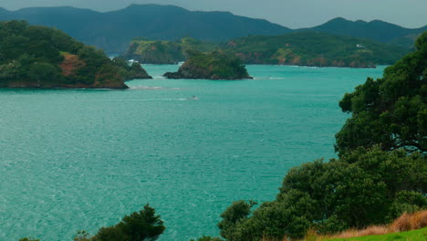 long-shot of a boat travelling between two islands, urupukapuka island, new zealand