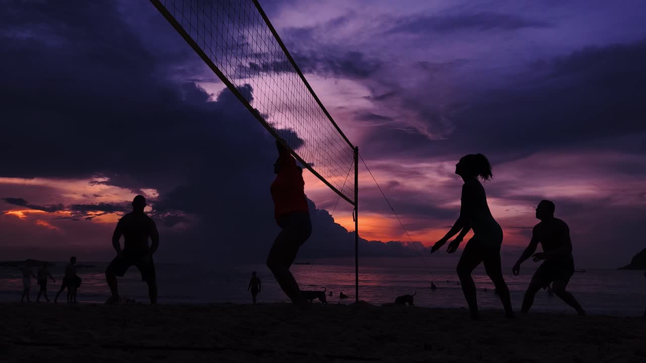 해가 지는 해변에서 배구 선수들이