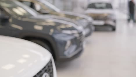la mano del hombre le da las llaves del coche a la mano de la mujer en el concesionario de automóviles de cerca. el concesionista le da la llave al nuevo propietario en una exposición de automóviles o salón.