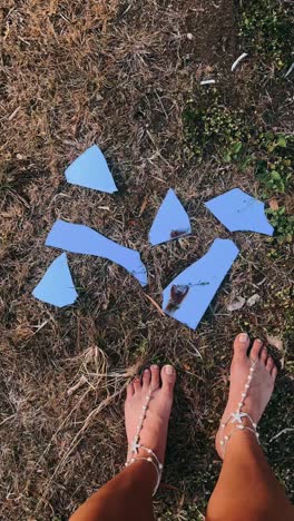 espejo roto en la hierba con los pies descalzos