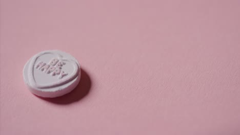 Hand,-Die-Herzbonbons-Mit-Romantischer-Nachricht-Aufhebt,-Sei-Glücklich-Auf-Rosa-Hintergrund