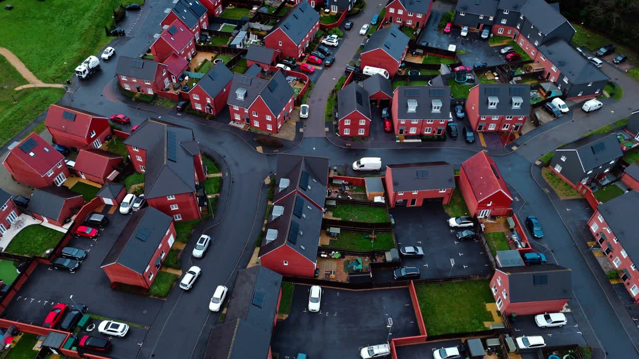 Luftoptagelser med drone over et lokalt engelsk forstadskvarter i det sydlige England ved tusmørke og solnedgang. Med befærdede veje og en rolig atmosfære med haver, træer og en dam