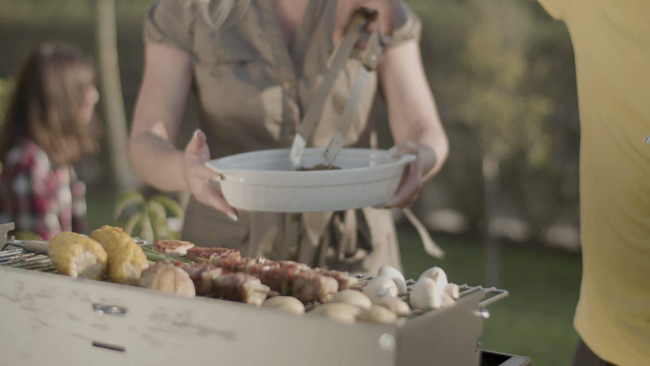 hombre en la parrilla poniendo costillas de cerdo en el plato de su esposa