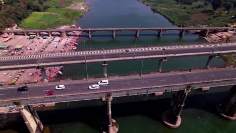 vehicles moving on Bridge with narmada river and farming lands at Jotpur, Jabalpur, madhya pradesh, india. day time, push back, tilt up, drone shot, 4k.